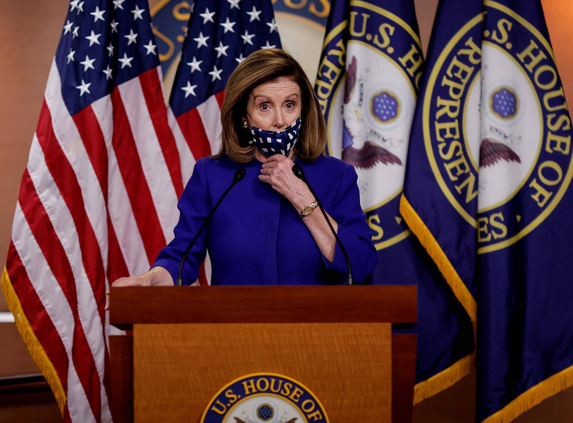 FILE PHOTO: U.S. House Speaker Nancy Pelosi adjusts her face mask as she announces her plans for Congress to create a "Commission on Presidential Capacity to Discharge the Powers and Duties of Office Act," after U.S. President Donald Trump came down with coronavirus disease (COVID-19), during a Capitol Hill news conference in Washington, U.S., October 9, 2020. REUTERS/Carlos Barria/File Photo