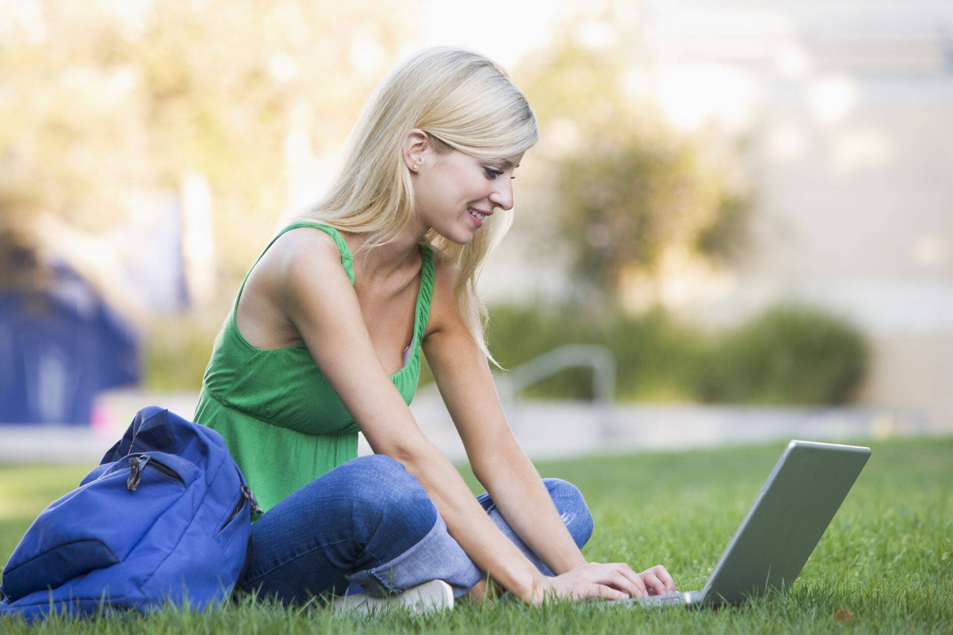 Woman outdoors sitting on grass with laptop (selective focus)