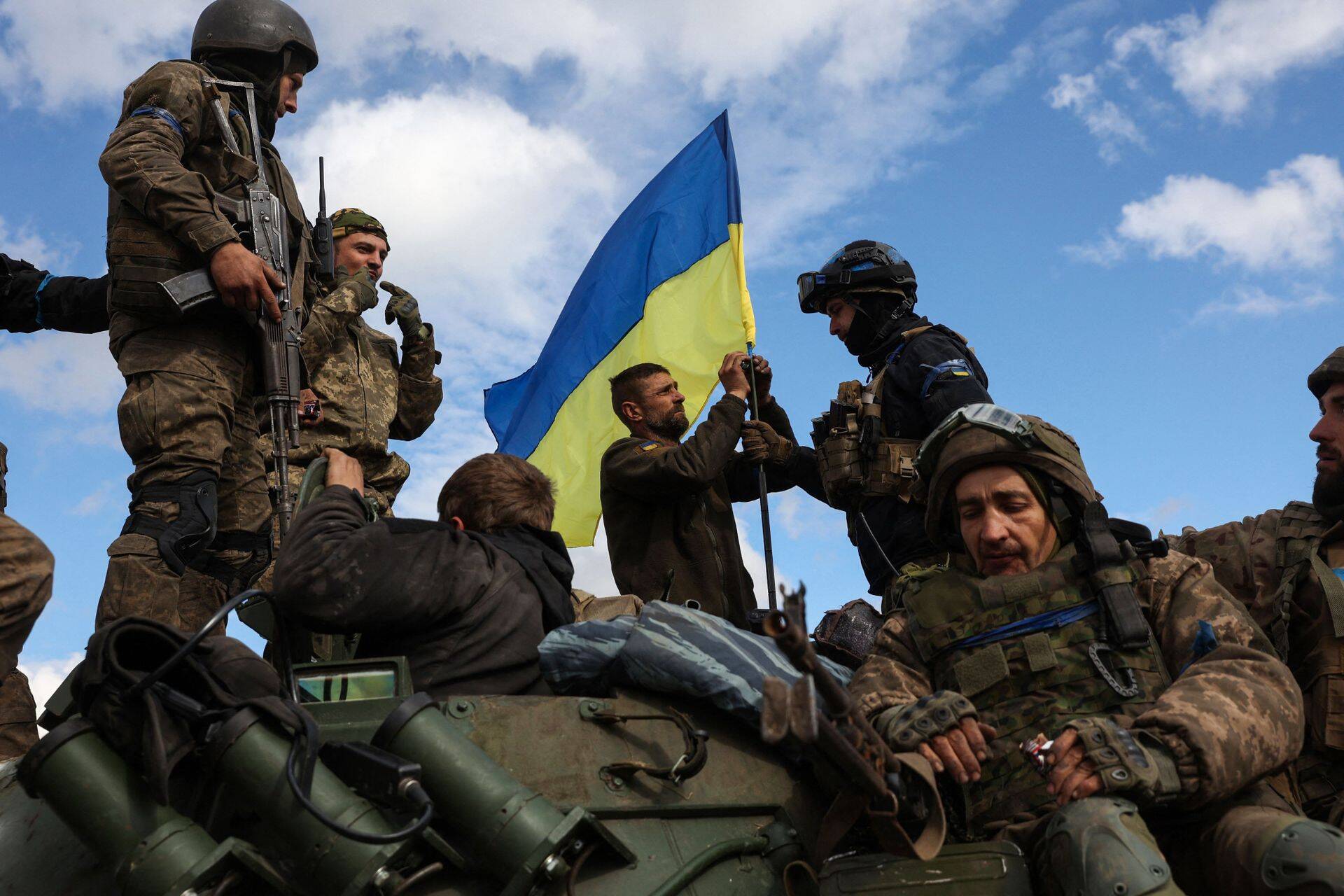 Украинские военные устанавливают национальный флаг на бронетранспортере на дороге под Лиманом.