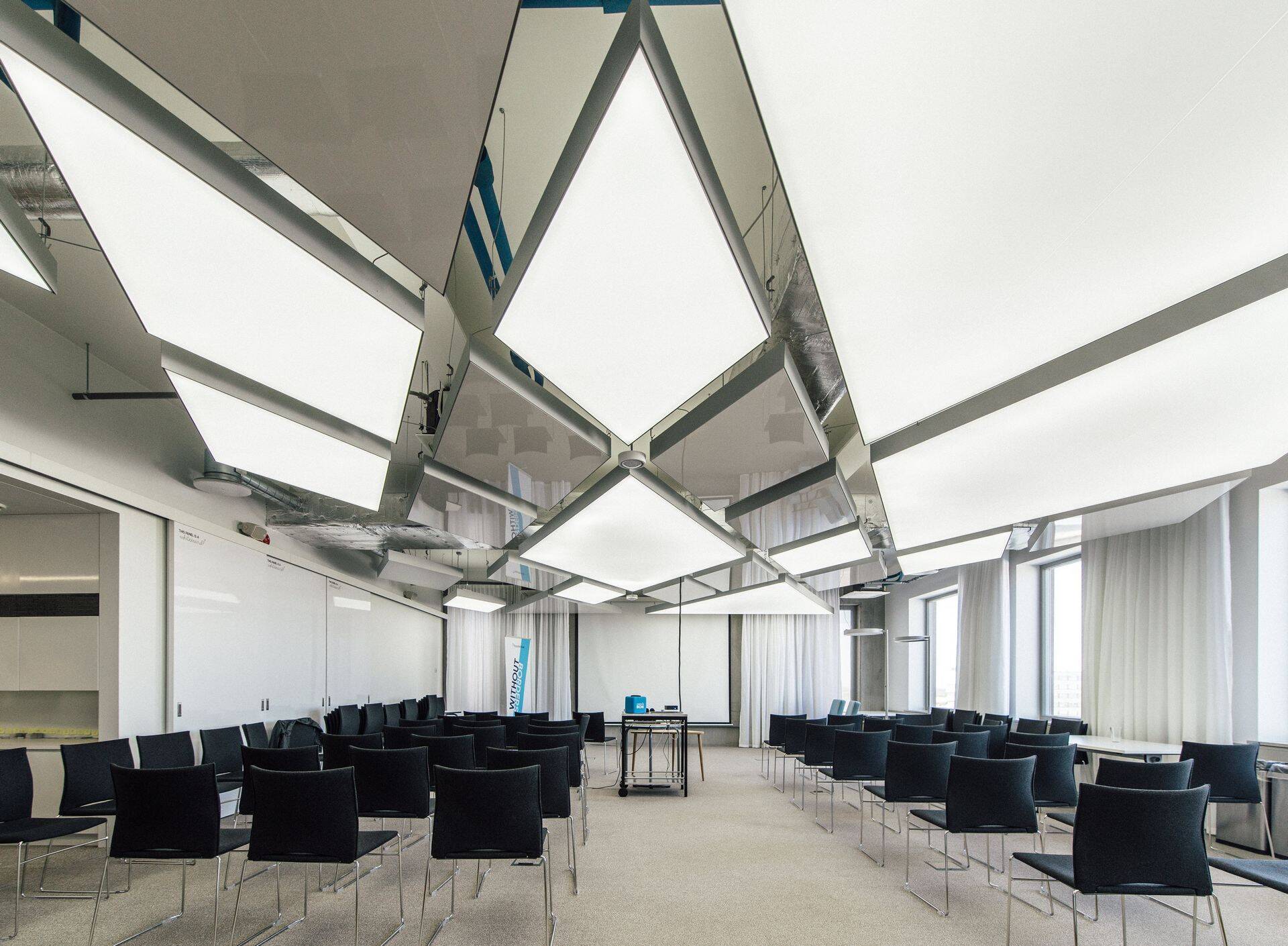 Ruumi suuremate koosolekute pidamiseks kaunistab nelinurksete plafoonvalgustitega lagi.