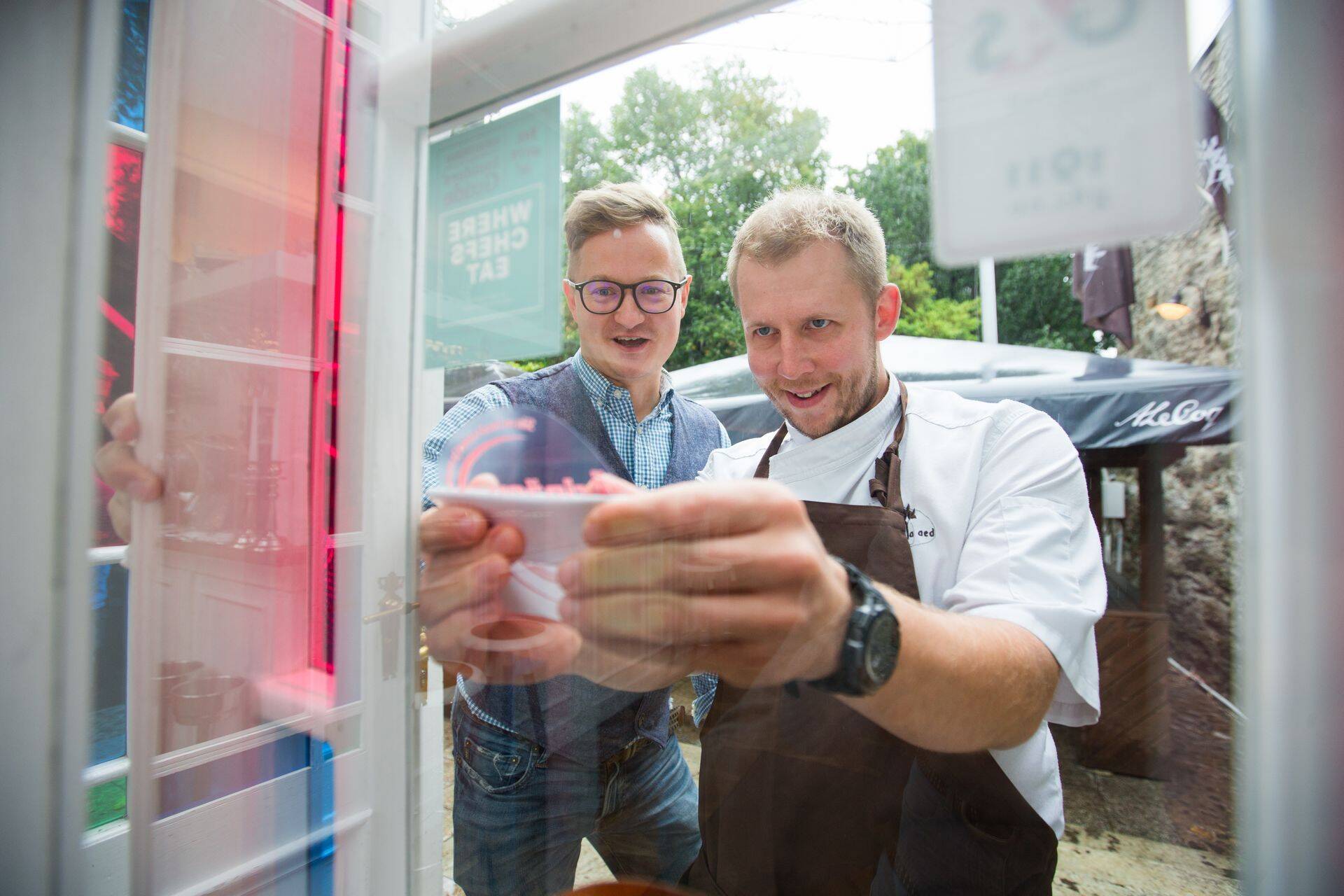 Restorani üks omanik ja sommeljee Kristjan Peäske (vasakul) koos peakokk Kristo Malmiga täna kätte saadud kleebist restorani sissepääse juurde liimimas.
