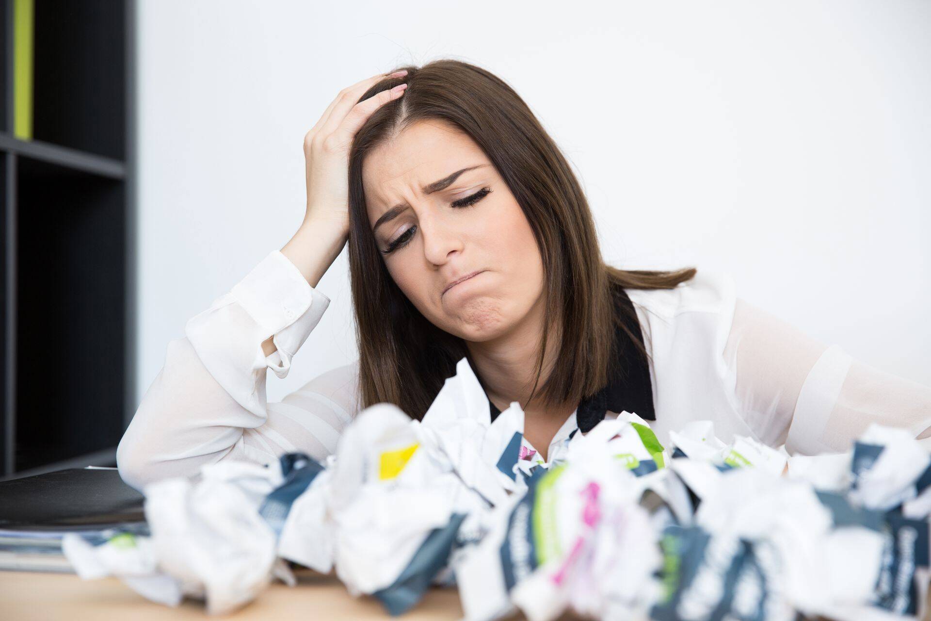 Tired businesswoman sitting at the table with trash papers