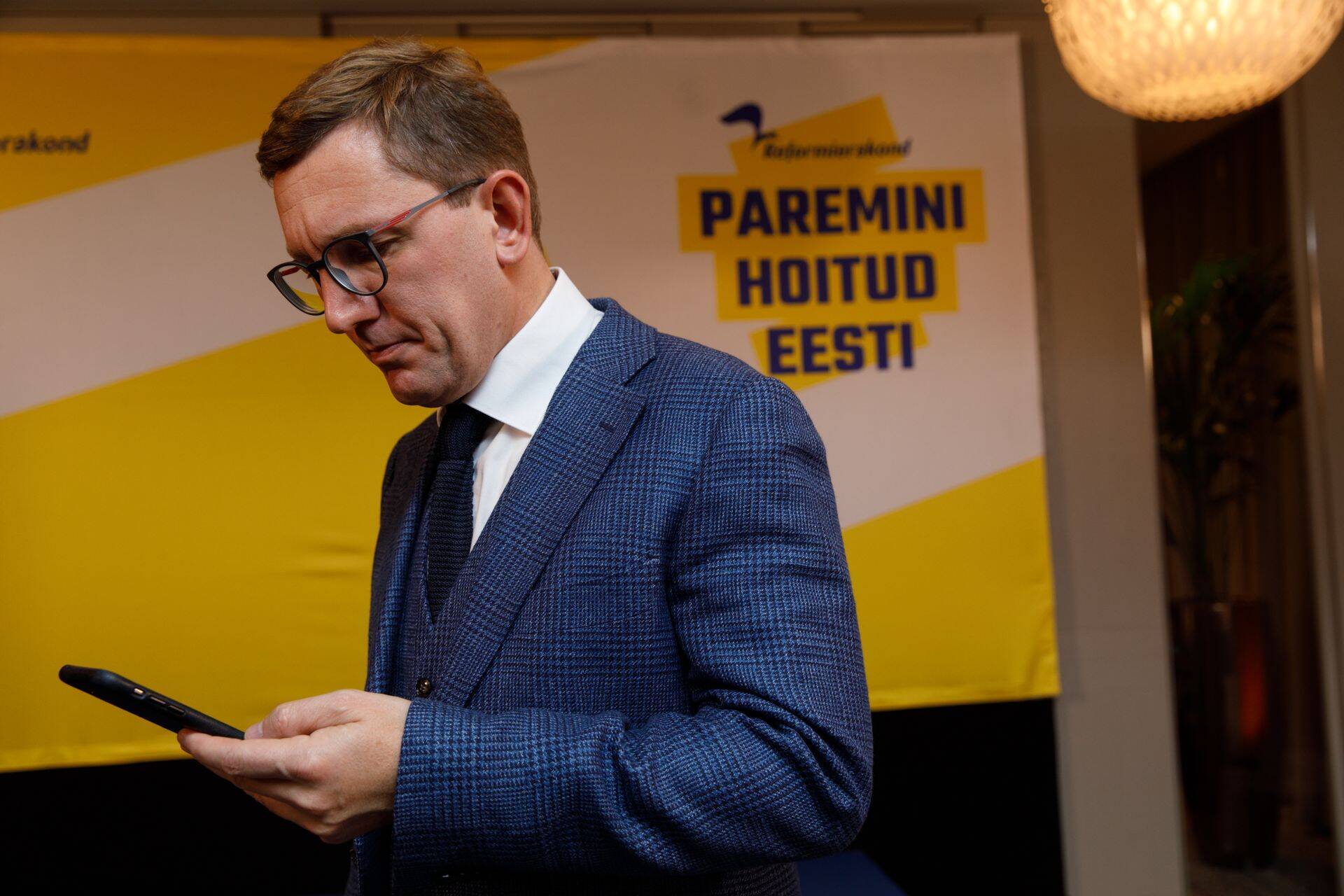 Кристен Михал, министр климата нового правительства на фоне агитационного плаката Партии реформ.