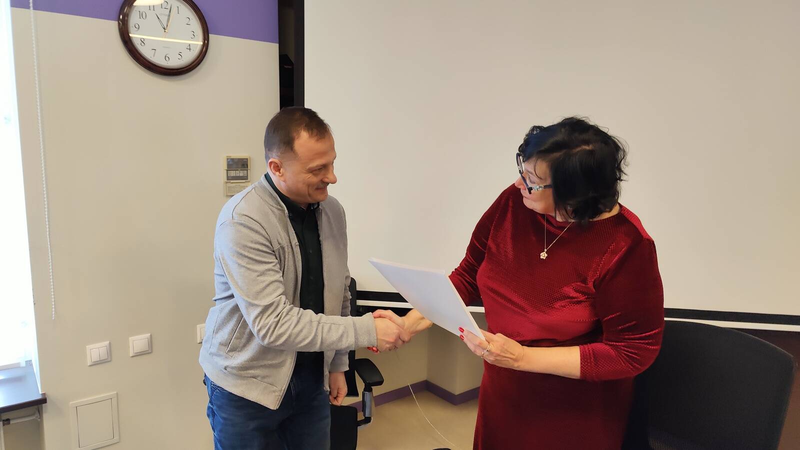 Катри Райк вручает Айвару Вирунену разрешение на эксплуатацию завода магнитов, выданное Департаментом архитектуры и городского планирования.