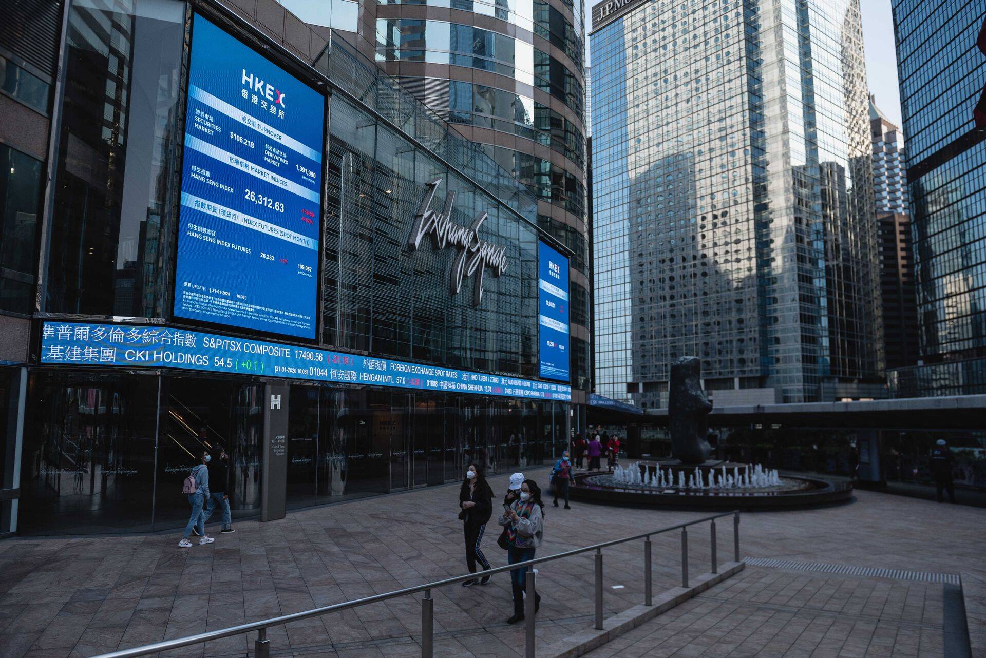 Passerby walk by the Hong Kong Stock Exchange building wearing masks..Citizens throughout Hong Kong are wearing face masks to prevent against the Coronavirus. Originating in Wuhan, China, the virus has spread beyond China's borders into Hong Kong as well as other countries abroad.