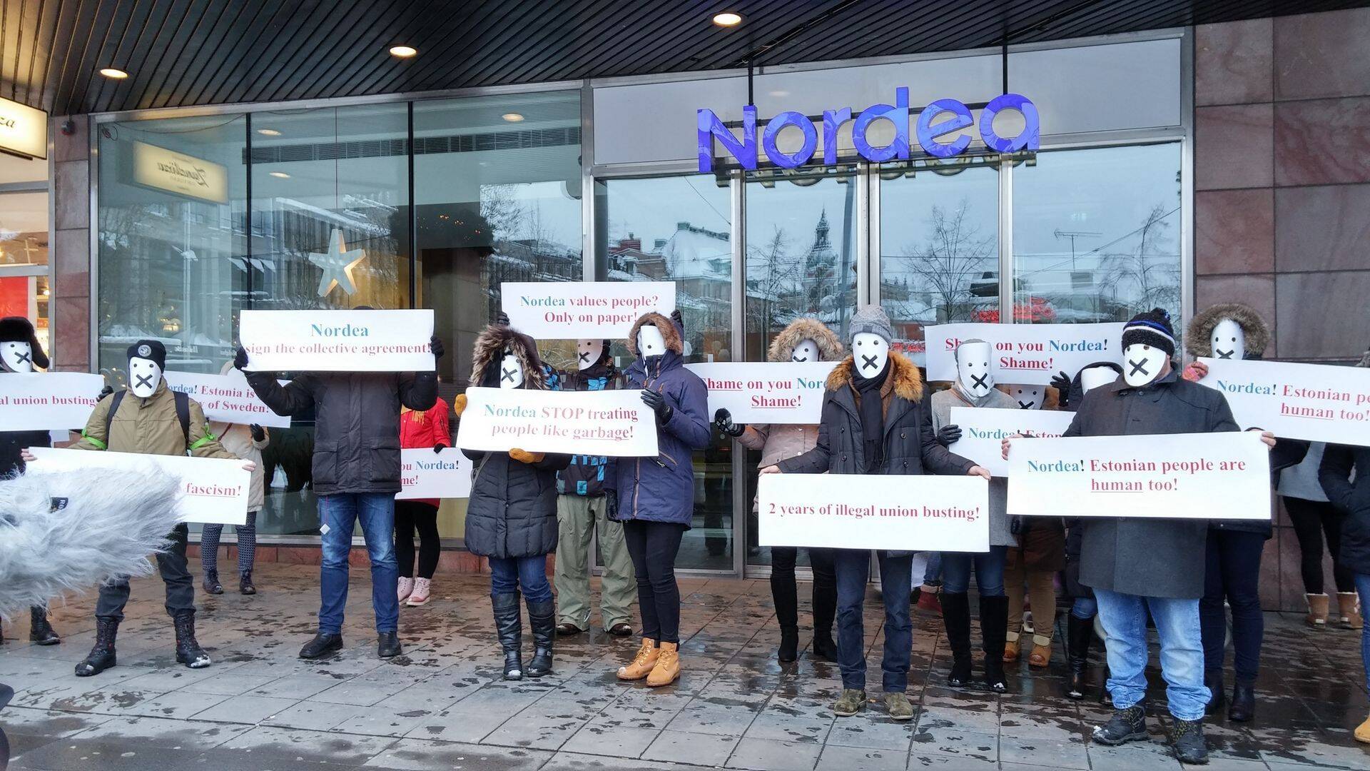 Nordea töötajad piketeerivad Nordea maja eest Rootsis. Plakatitel kirjad "Nordea=corporate fascism!" ja "Nordea sign the collective agreement".