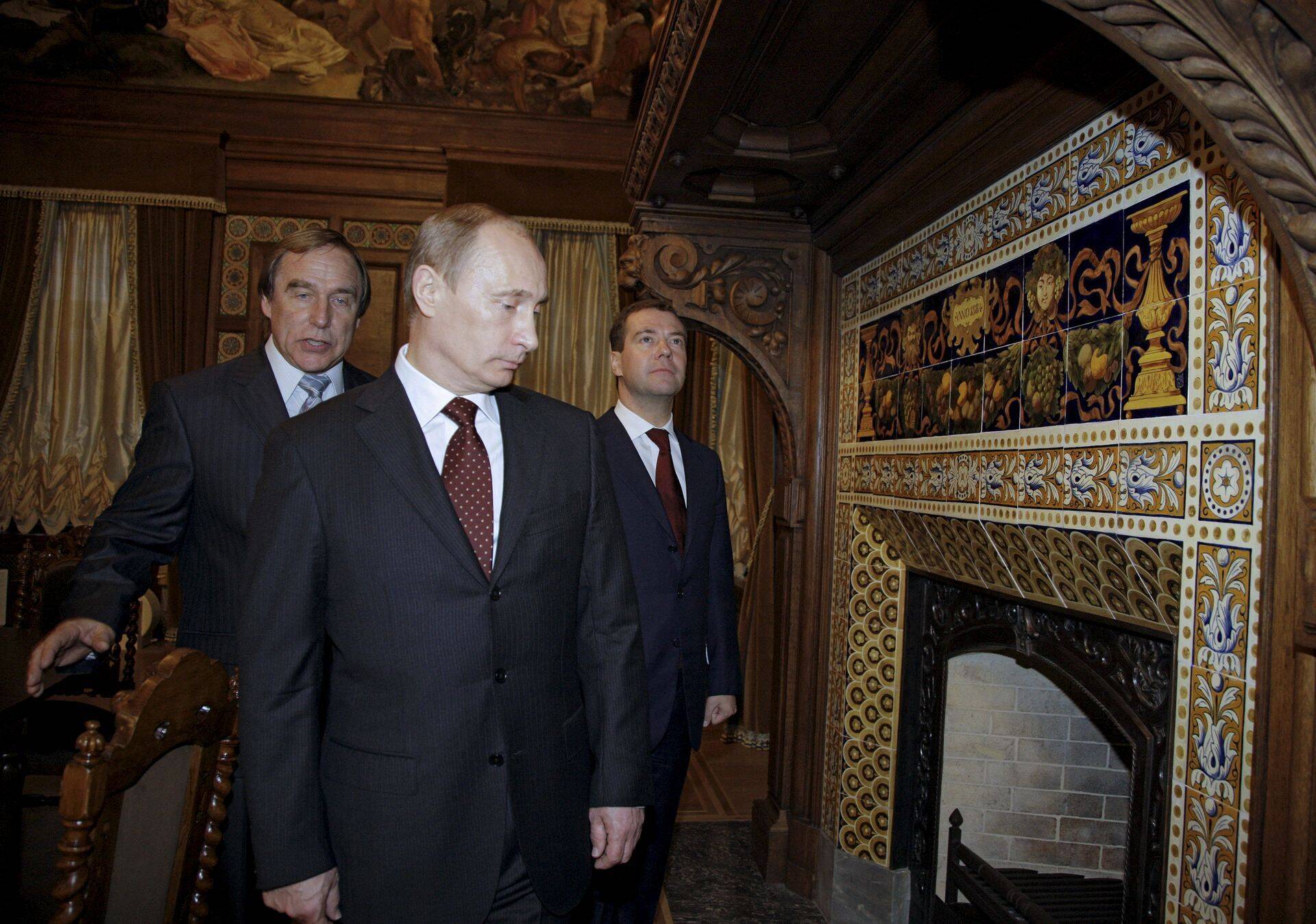 Vladimir Putin ja Dmitri Medvedev aastal 2009 jalutuskäigul Peterburi Muusikamajas, teejuhiks maja kunstiline juht, tšellist ja Putini sõber Sergei Roldugin.