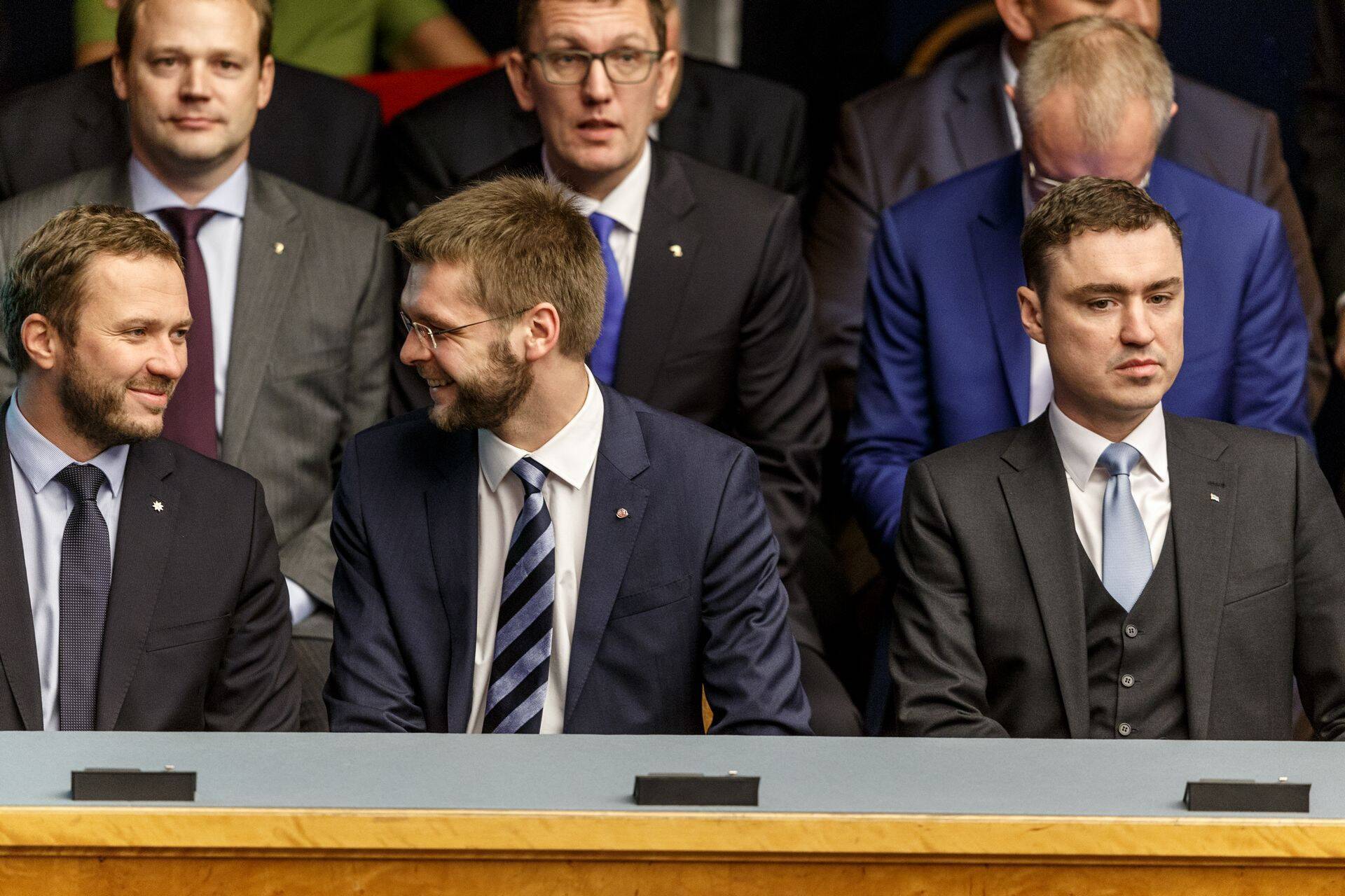 Morni näoga ekspeaminister Taavi Rõivas riigikogus uue valitsuse ametisse astumise istungil. Tema kõrval rõõmustavad koalitsiooni jäänud IRLi juht Margus Tsahkna ja sotside esimees Jevgeni Ossinovski.