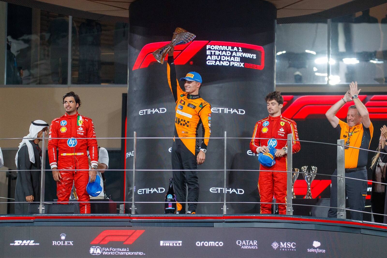 McLarenil Abu Dhabis võitnud Lando Norris pjedestaalil. Intervjueeritav Zak Brown on pildil paremal.