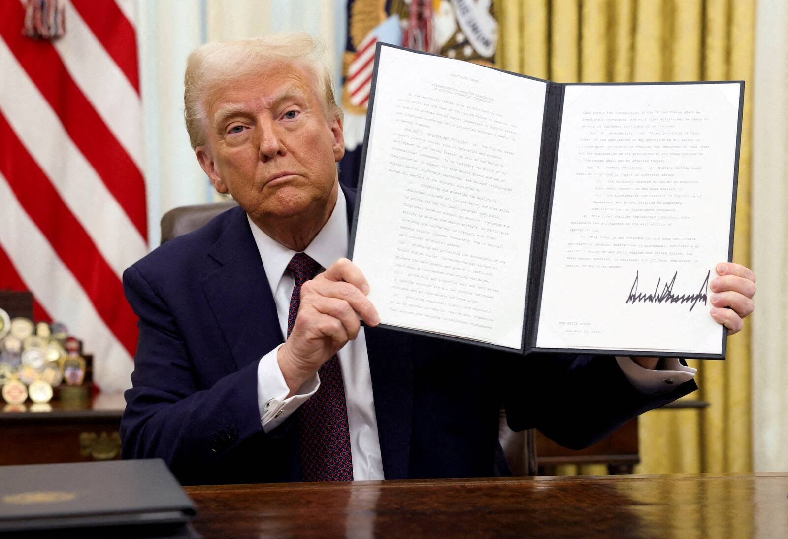 Президент США Дональд Трамп держит подписанный в Овальном кабинете Белого дома указ о криптовалютах.