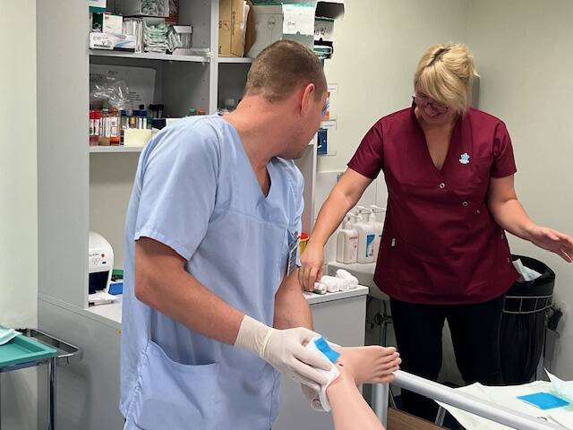 Õe õppekava tudeng ja hooldustöötaja õppekava õpilane ühiselt ülesannet lahendamas.