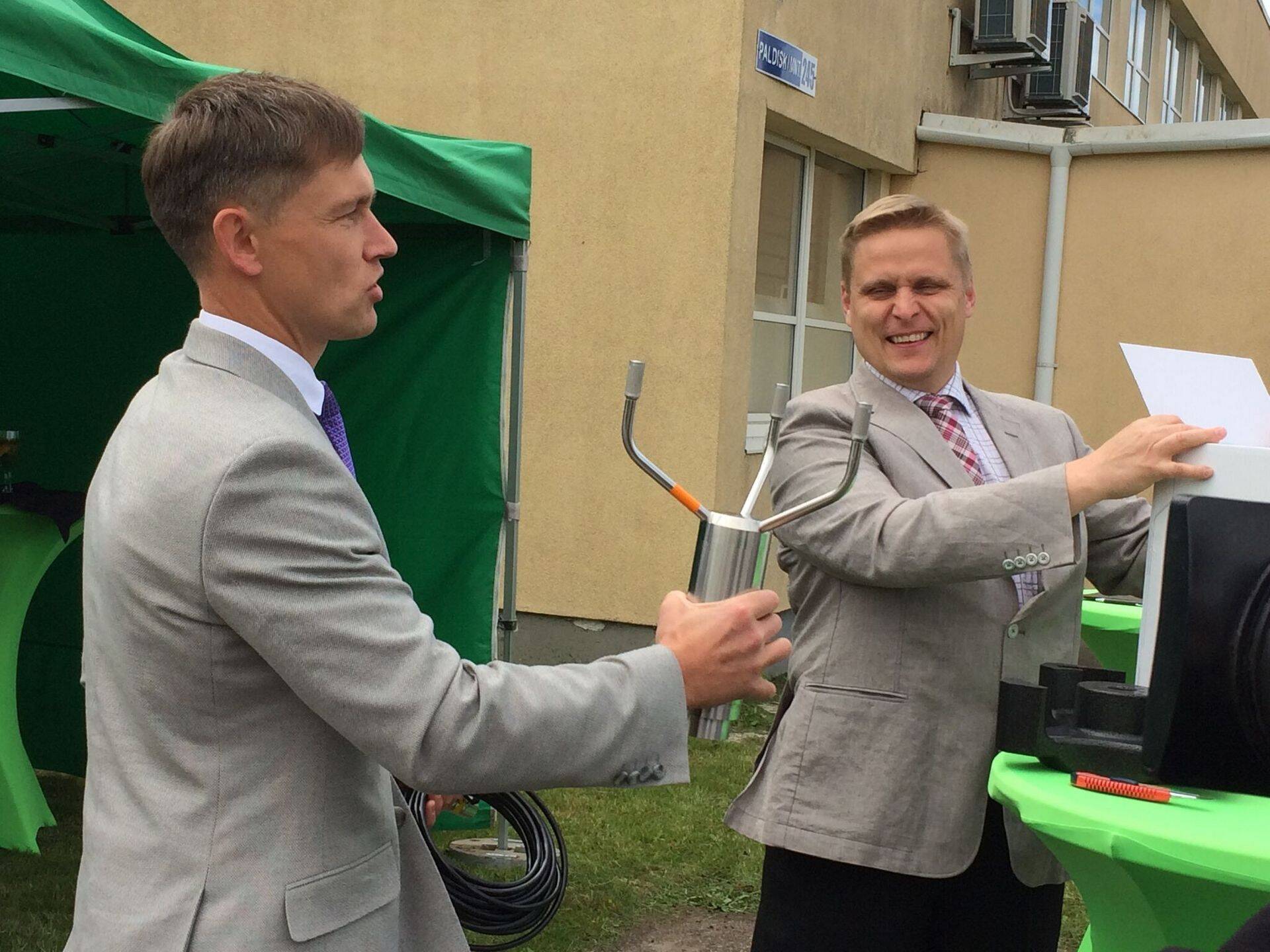 Keskkonnaagentuuri direktor Taimar Ala rõõmustab uue ilmavaatlusvõrgu tehnika üle, mis paigaldatakse peagi mõnda Eestis asuvasse ilmavaatlusjaama. Paremal automaatjaamad tootnud ning need pidulikult üle andnud Soome firma Vaisala OY Balti regiooni müügijuht Jukka Sihvola.