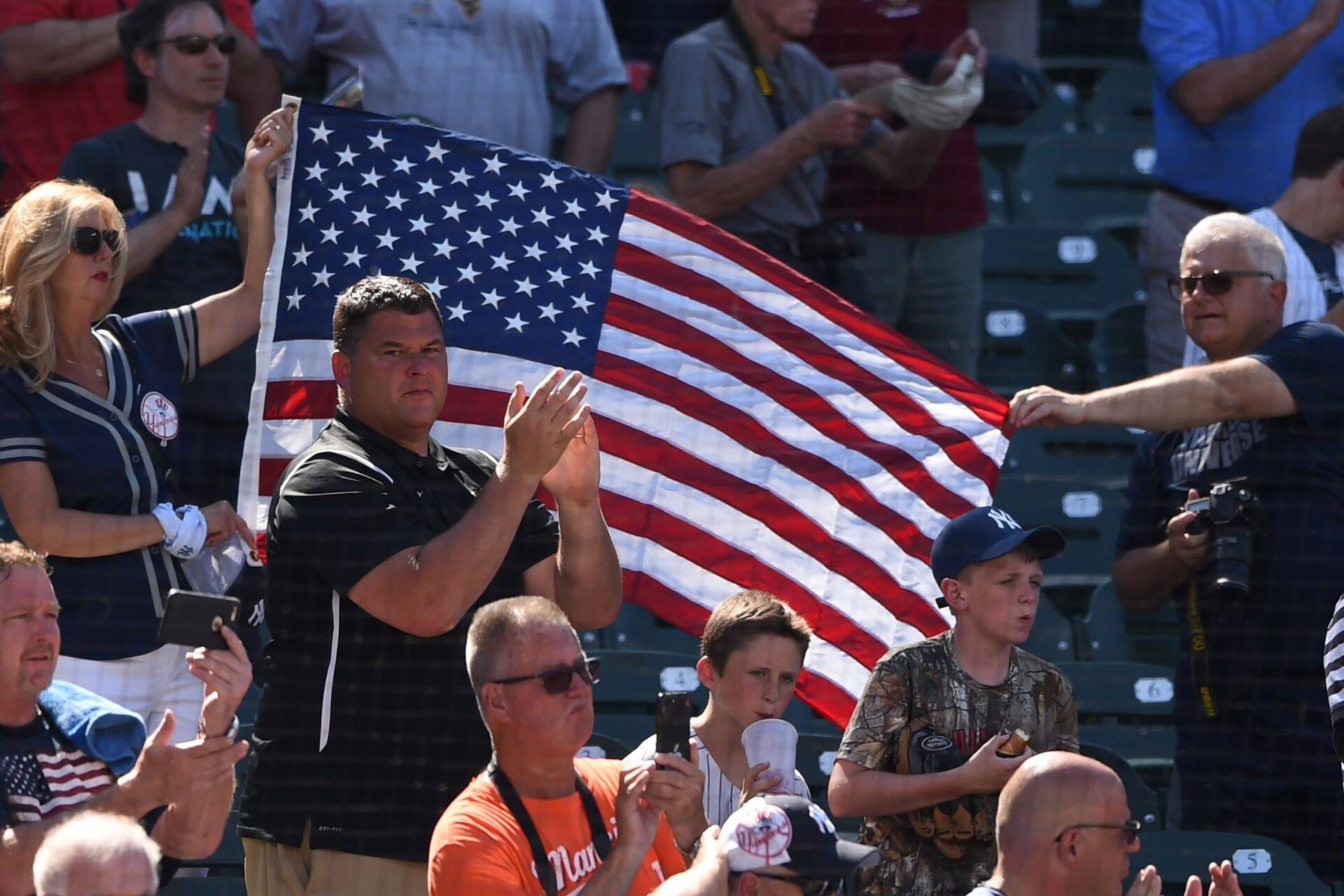 BALTIMORE, MD - JULY 09: Fans hold the flag during the National Anthem during a game one of a doubleheader baseball game between the New York Yankees and the Baltimore Orioles at Oriole Park at Camden Yards on July 9, 2018 in Baltimore, Maryland. Mitchell Layton/Getty Images/AFP== FOR NEWSPAPERS, INTERNET, TELCOS & TELEVISION USE ONLY ==