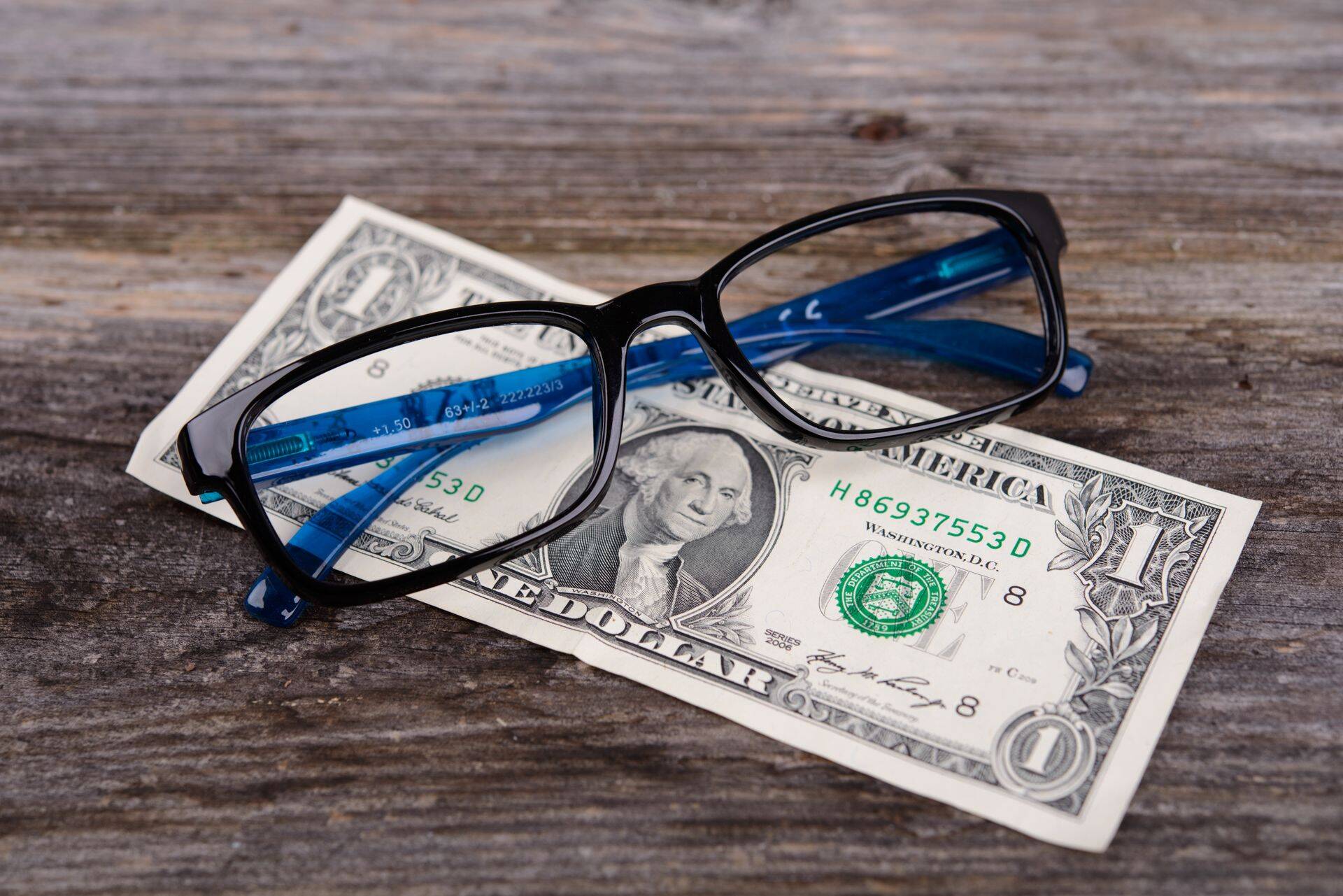 glasses frame with money on wooden ground
