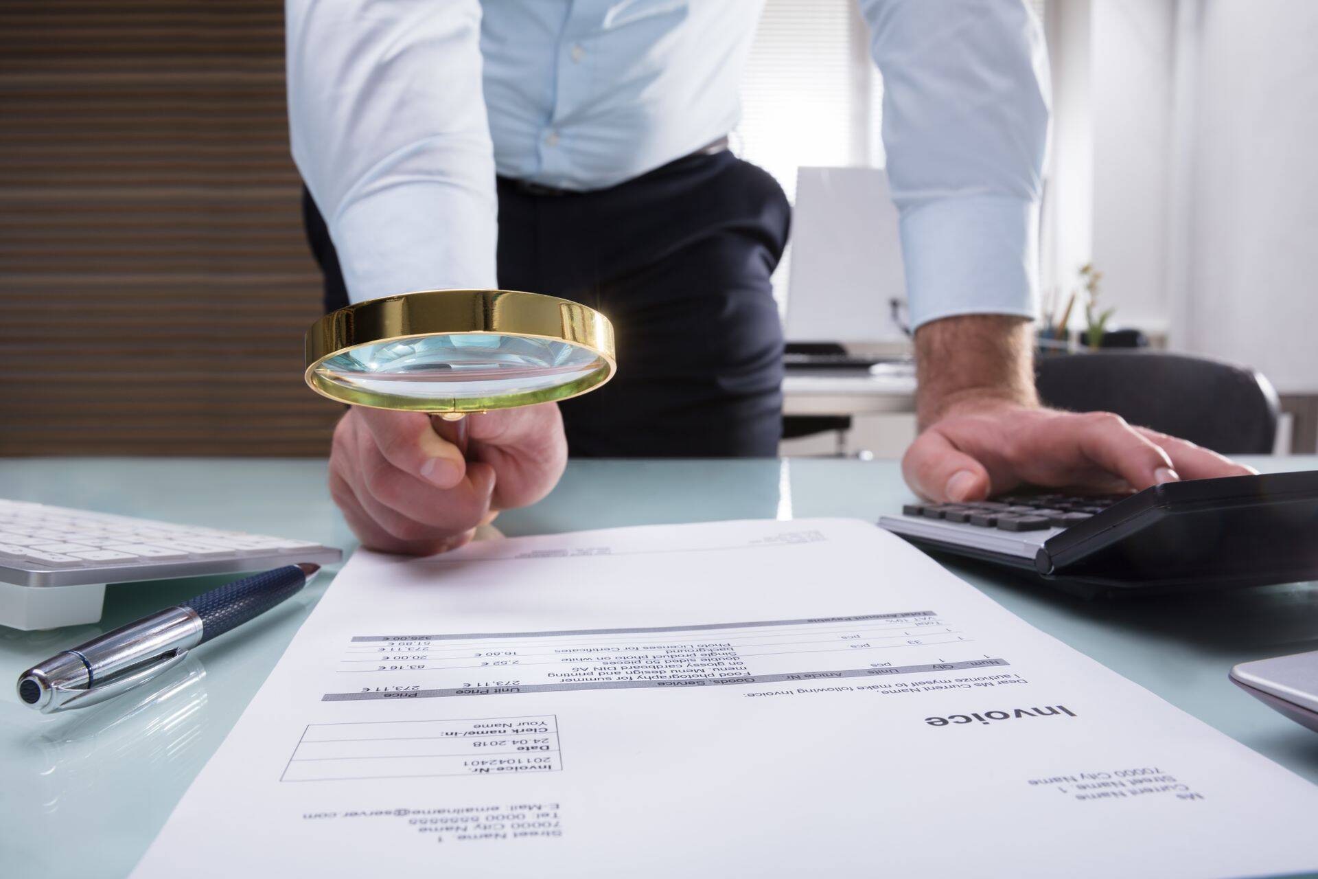 Human Hand Holding Magnifying Glass Over Invoice