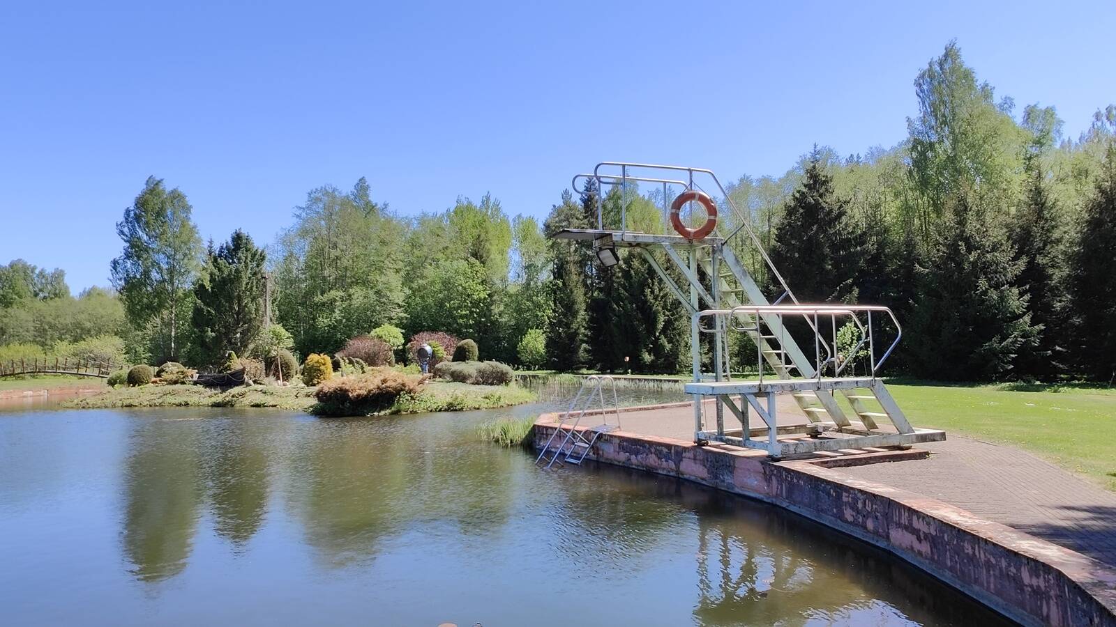 На хуторе есть вышка для прыжков в воду. А за ней виднеется остров, на который можно попасть по мостику.