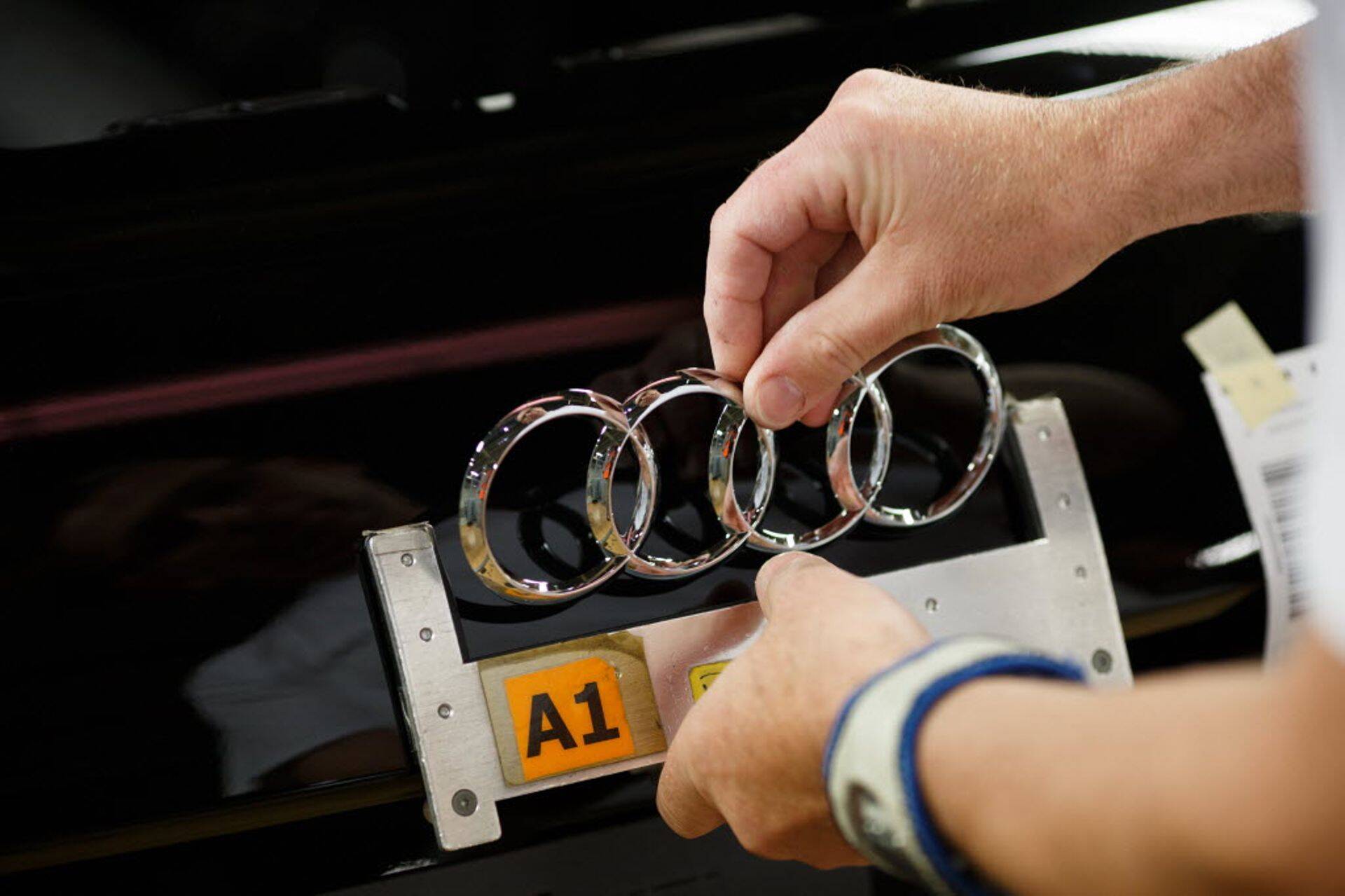 Töötaja paigaldab Audi sõiduautole logo